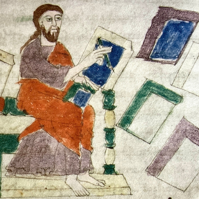 Miniatura medievale che raffigura un uomo seduto con barba e tunica, impegnato nella scrittura o nella lettura di un codice blu; attorno a lui sono sparsi altri fogli o tavolette colorate, rappresentati in prospettiva semplice.