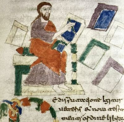 Miniatura medievale che raffigura un uomo seduto con barba e tunica, impegnato nella scrittura o nella lettura di un codice blu; attorno a lui sono sparsi altri fogli o tavolette colorate, rappresentati in prospettiva semplice.